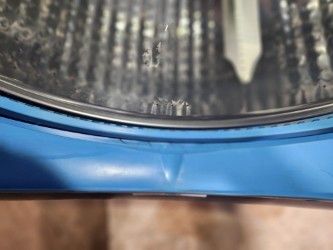 Close-up view of a blue plastic container or basin with a textured black surface or mat inside it