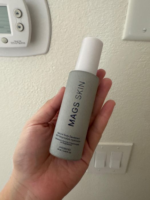 Customer holding a MAGS Skin deodorant spray bottle