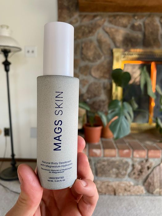 Customer holding a MAGS Skin deodorant bottle at home