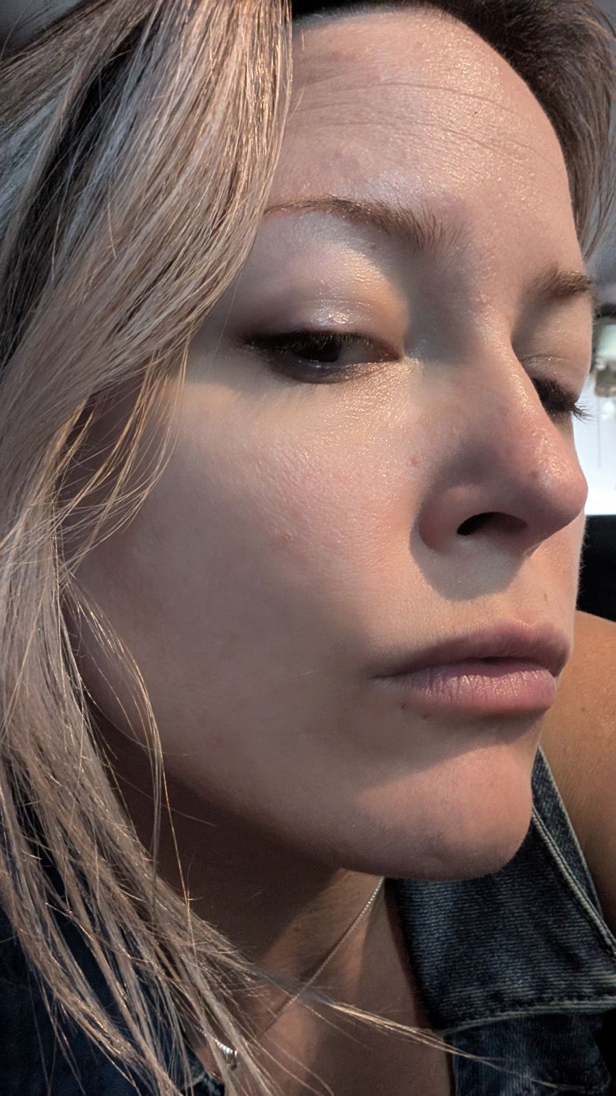 Close-up profile view of a woman with blonde hair and natural makeup looking to the side