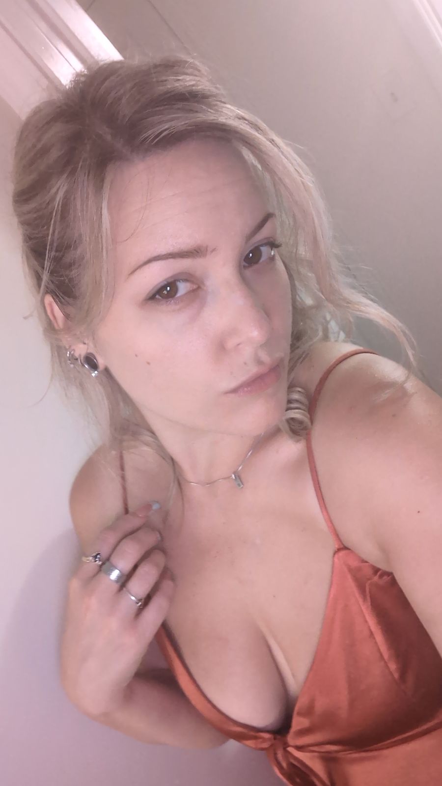 Woman taking a selfie indoors wearing an orange top